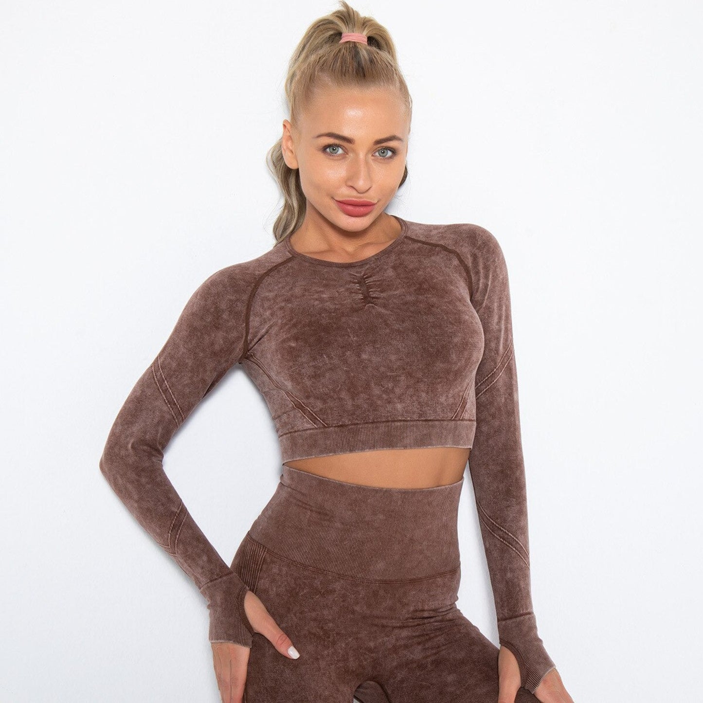 MODEL WEARING ARIA WORKOUT CROP TOP IN BROWN FEATURING THUMBHOLES ON SLEEVES, FROM VIBRAS ACTIVEWEAR.