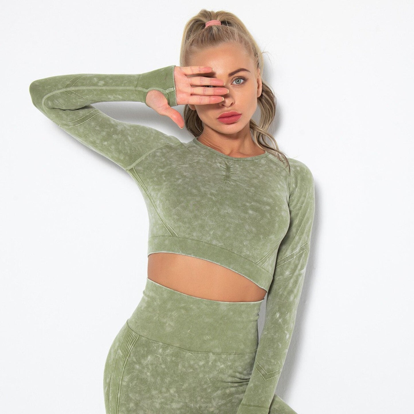MODEL WEARING ARIA WORKOUT CROP TOP IN GREEN FEATURING THUMBHOLES ON SLEEVES, FROM VIBRAS ACTIVEWEAR.