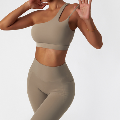 Fitness model wearing a one shoulder, sexy and squat proof matching set in the colour oatmeal from vibras activewear.