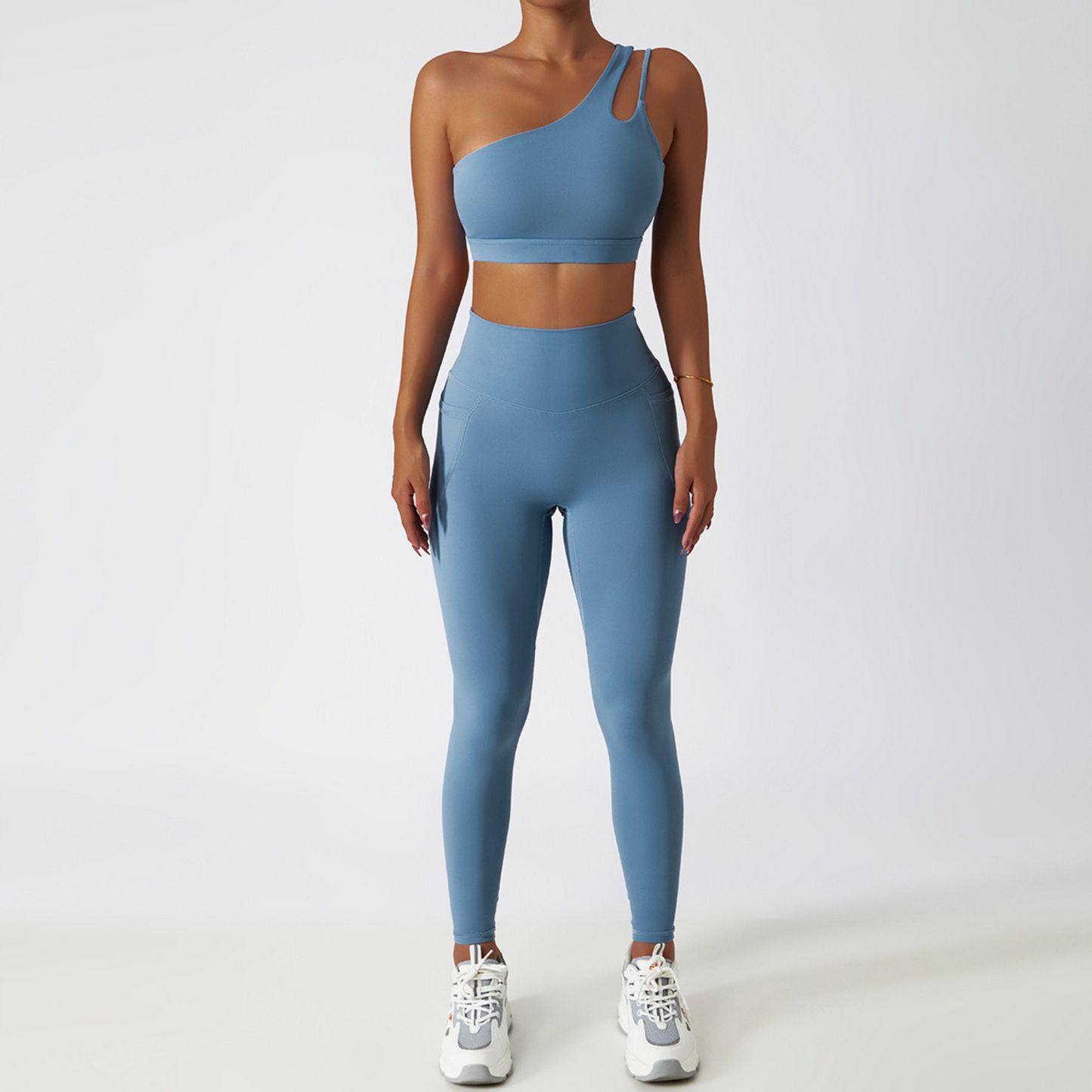 Fitness model wearing a one shoulder, sexy and squat proof matching set in the colour azure from vibras activewear.