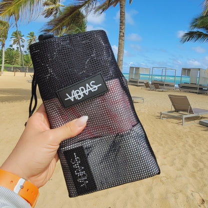 a female hand holding a set of Thick Marbled booty bands in a mash bag to workout at the beach
