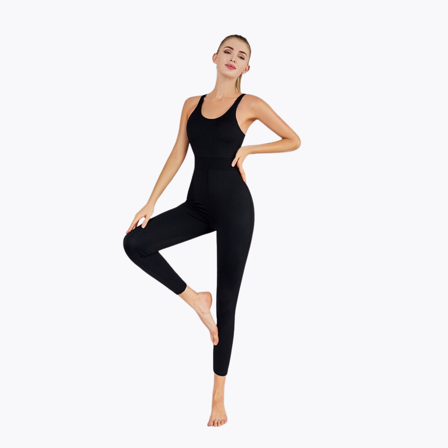 FITNESS MODEL POSING IN A BLACK JUMPSUIT FROM VIBRAS ACTIVEWEAR ON A WHITE BACKGROUND.