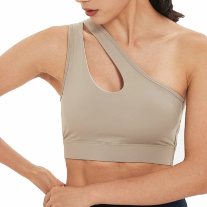 FITNESS MODEL WEARING A ONE SHOULDER, PEEK-A-BOO NECKLINE, TAN, HIGH IMPACT SPORTS BRA FROM VIBRAS ACTIVEWEAR.